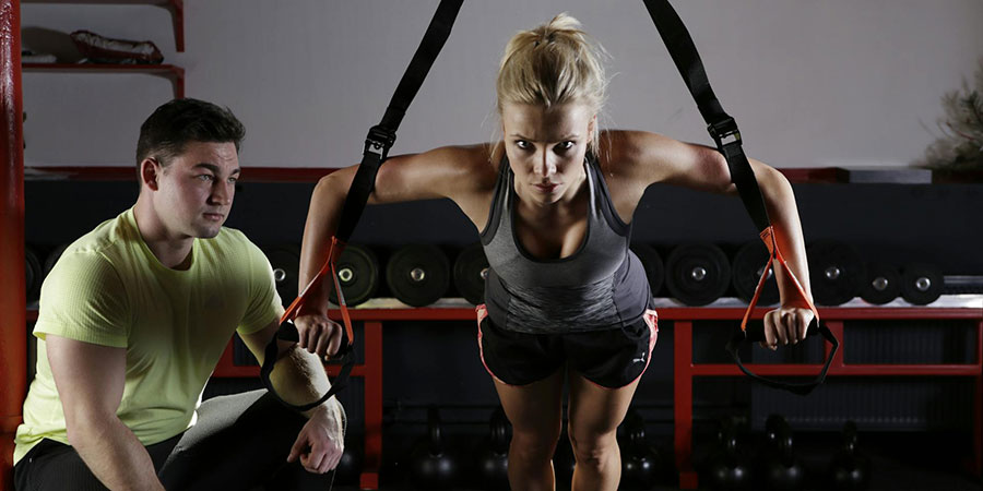 a woman working out with a trainer at the gym